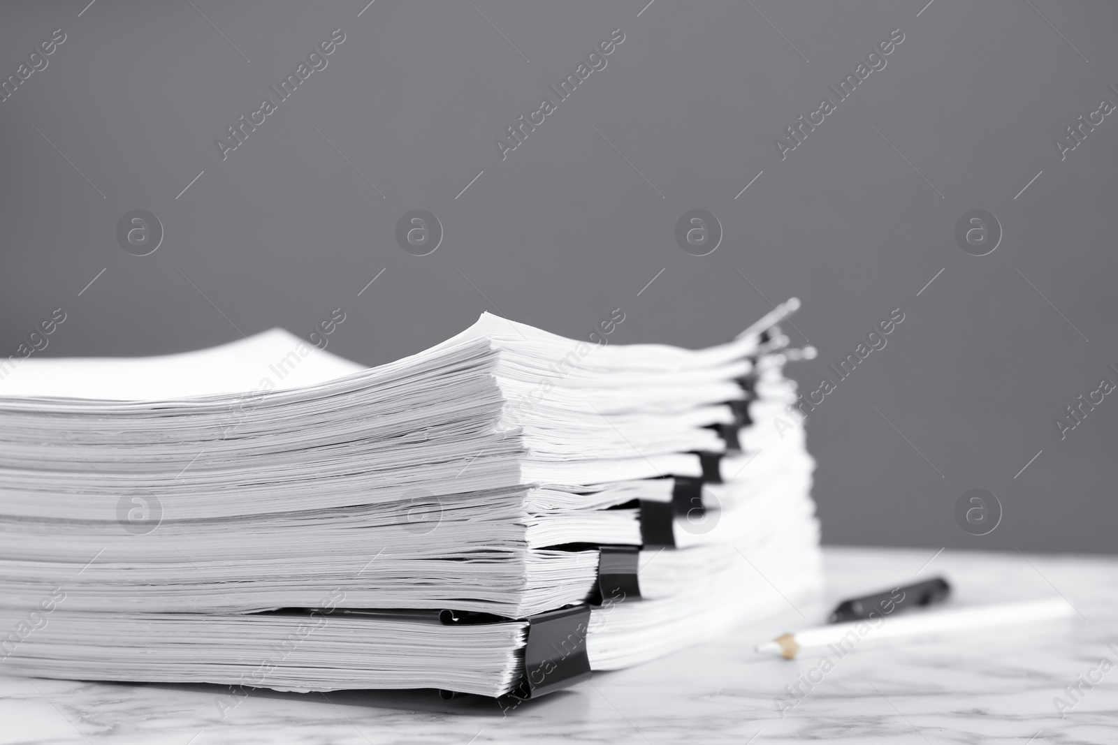 Photo of Stack of documents with binder clips on marble table against grey background