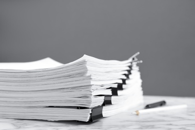 Stack of documents with binder clips on marble table against grey background