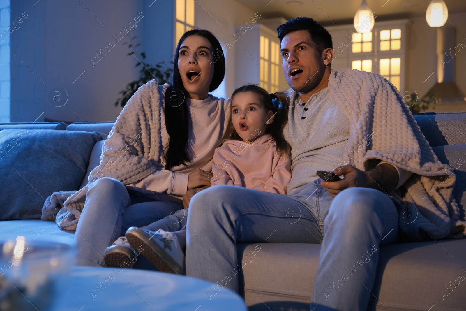 Photo of Family watching movie on sofa at night