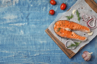 Photo of Fresh raw salmon steak with seasonings on wooden background, top view