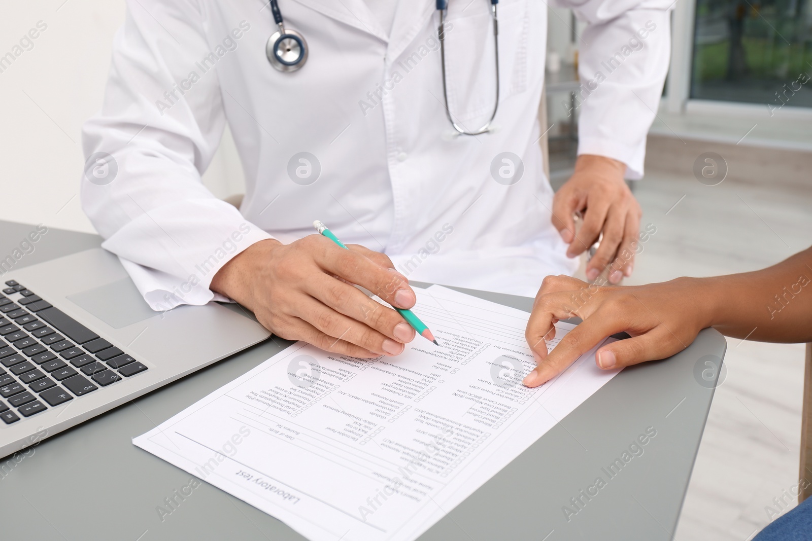 Photo of Male doctor working with patient at table in hospital, closeup