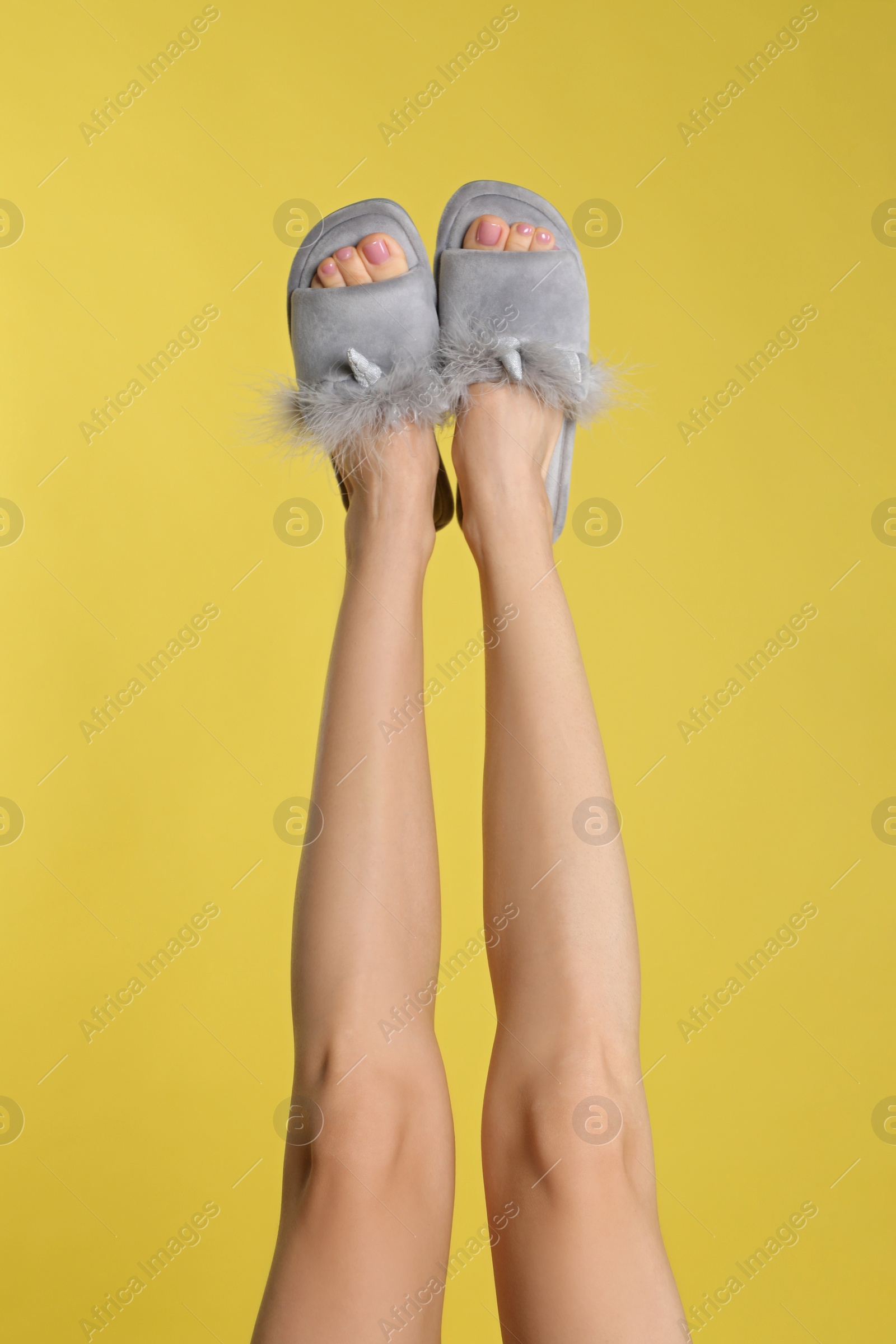 Photo of Woman wearing stylish slippers on yellow background, closeup