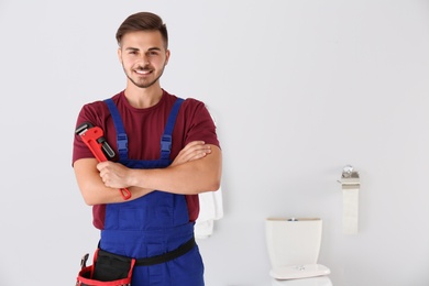 Photo of Young man with plumber wrench and toilet bowl on background