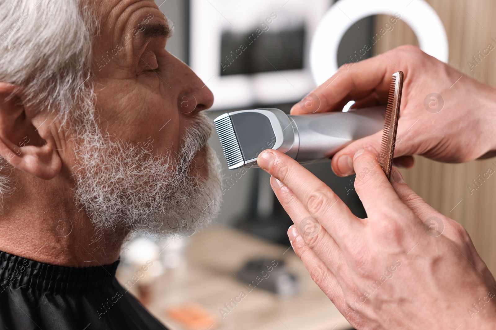 Photo of Professional barber trimming client's mustache in barbershop