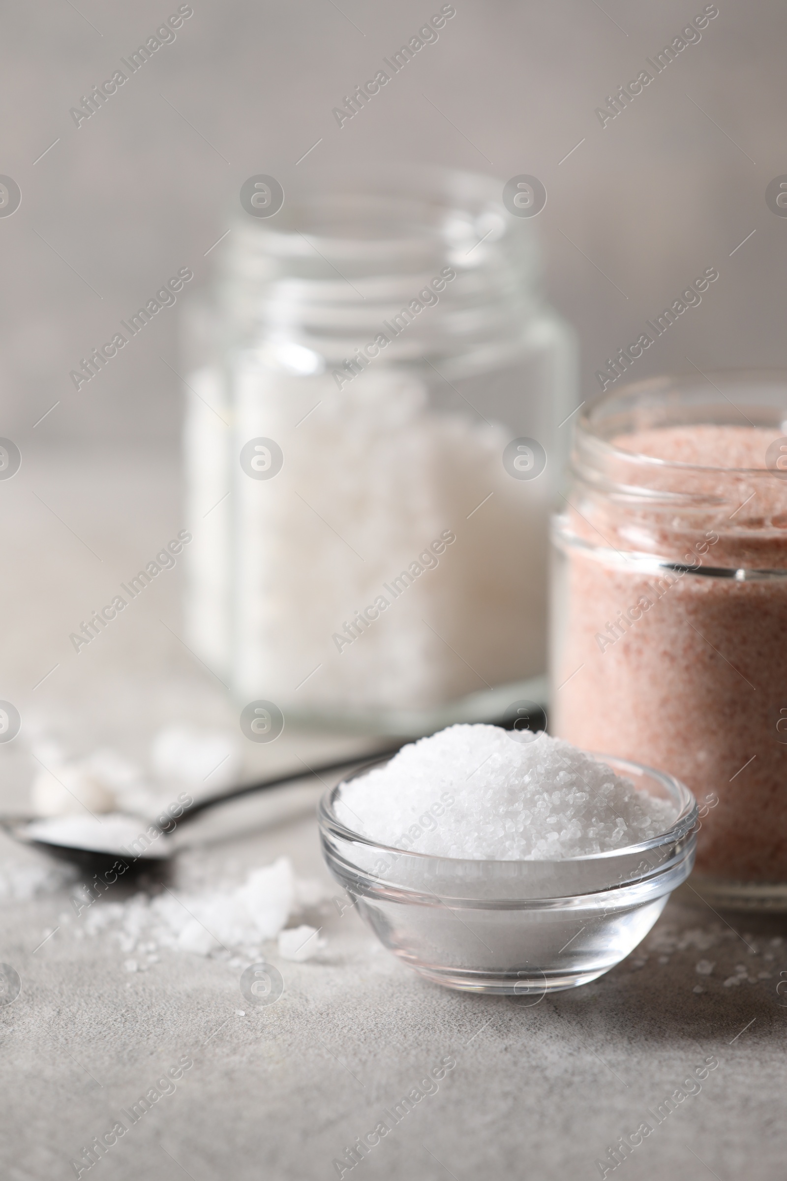 Photo of Different natural salt on grey table, closeup