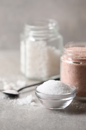 Photo of Different natural salt on grey table, closeup