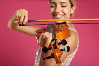 Photo of Beautiful woman playing violin on pink background, closeup