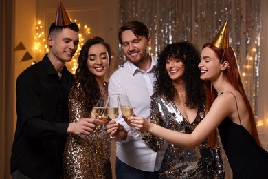 Photo of Happy friends clinking glassessparkling wine at birthday party indoors