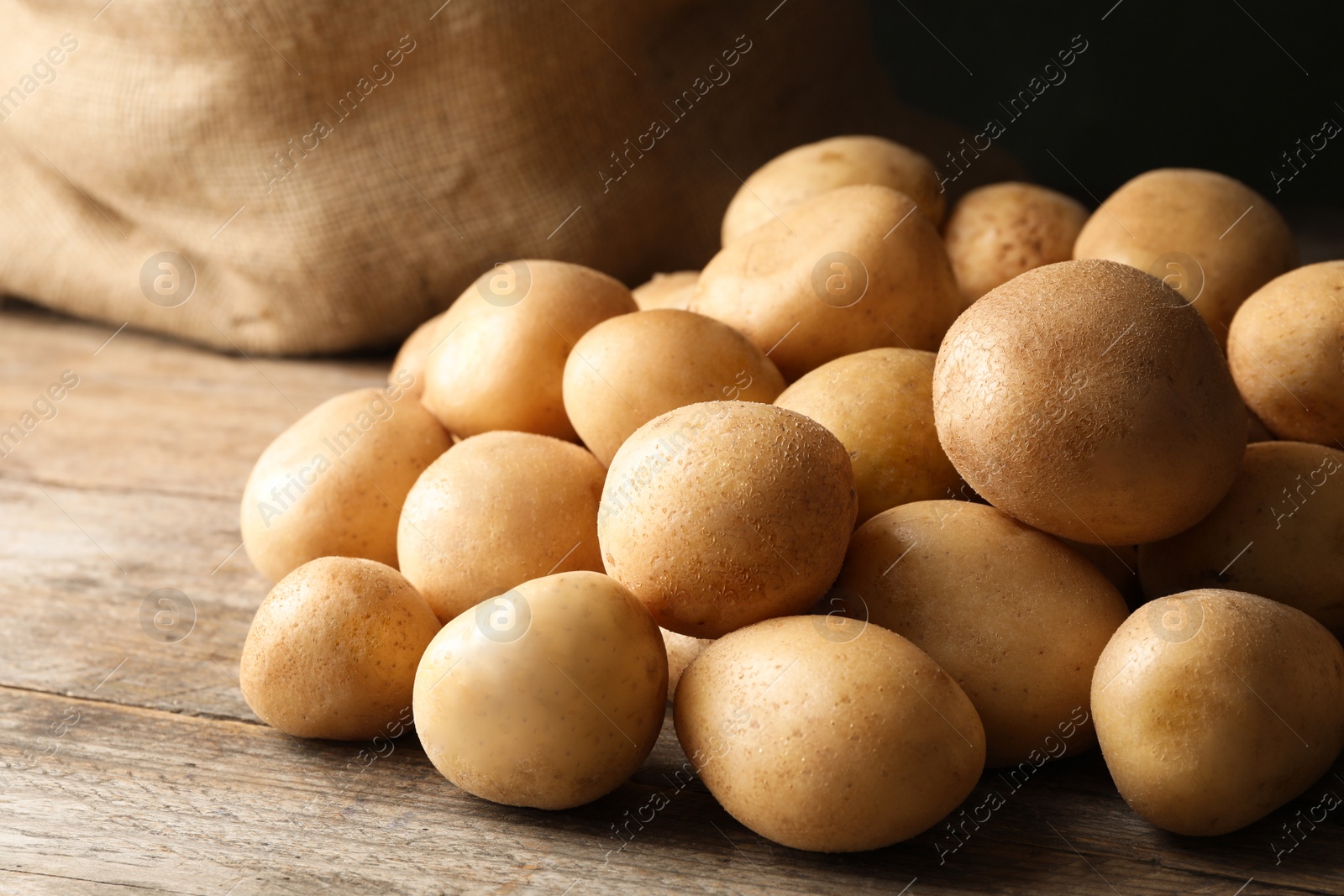 Photo of Raw fresh organic potatoes on wooden table