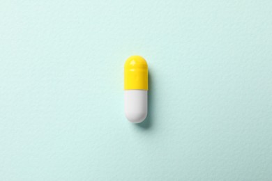 One colorful pill on mint background, top view