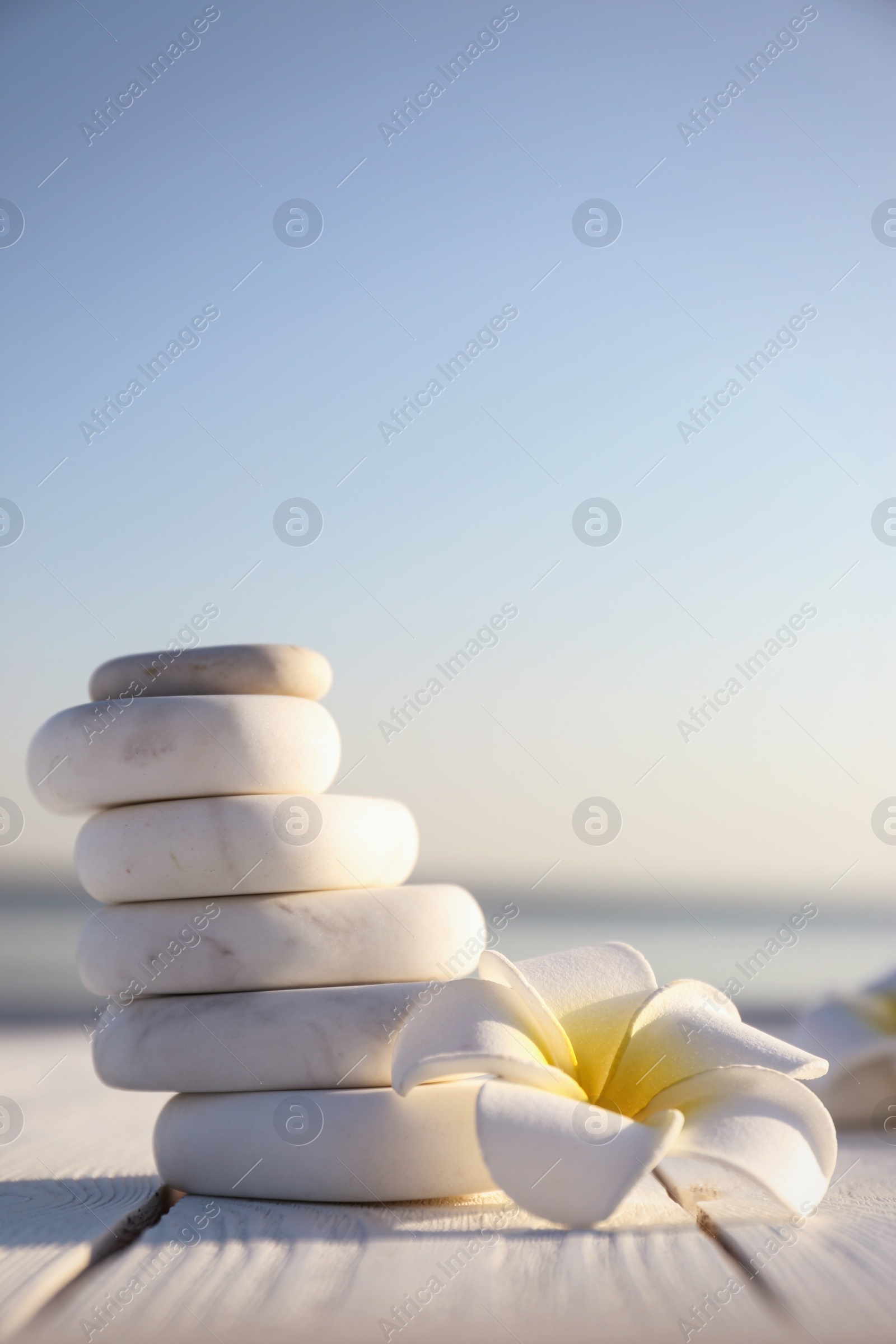 Photo of Stack of white marble stones and beautiful flower on wooden deck, space for text. Zen concept