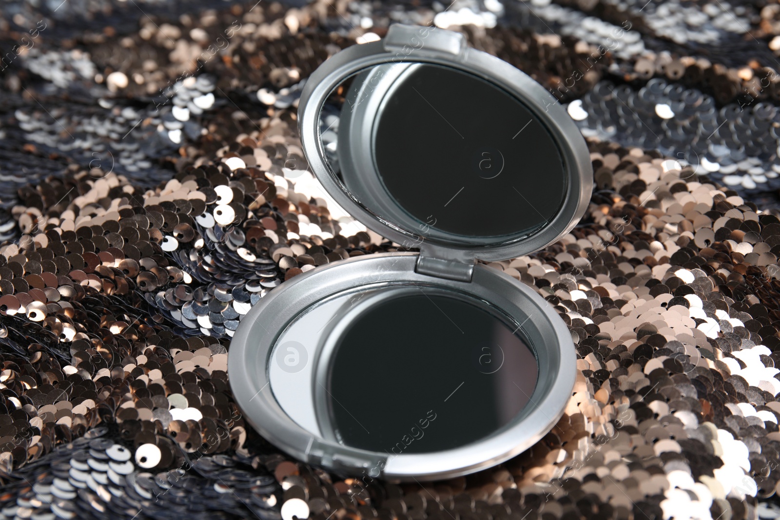 Photo of Grey cosmetic pocket mirror on shiny fabric