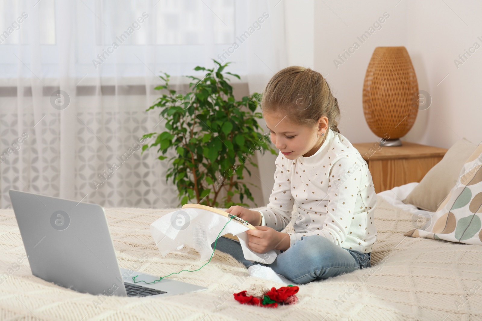 Photo of Little girl learning to embroider with online course at home. Time for hobby