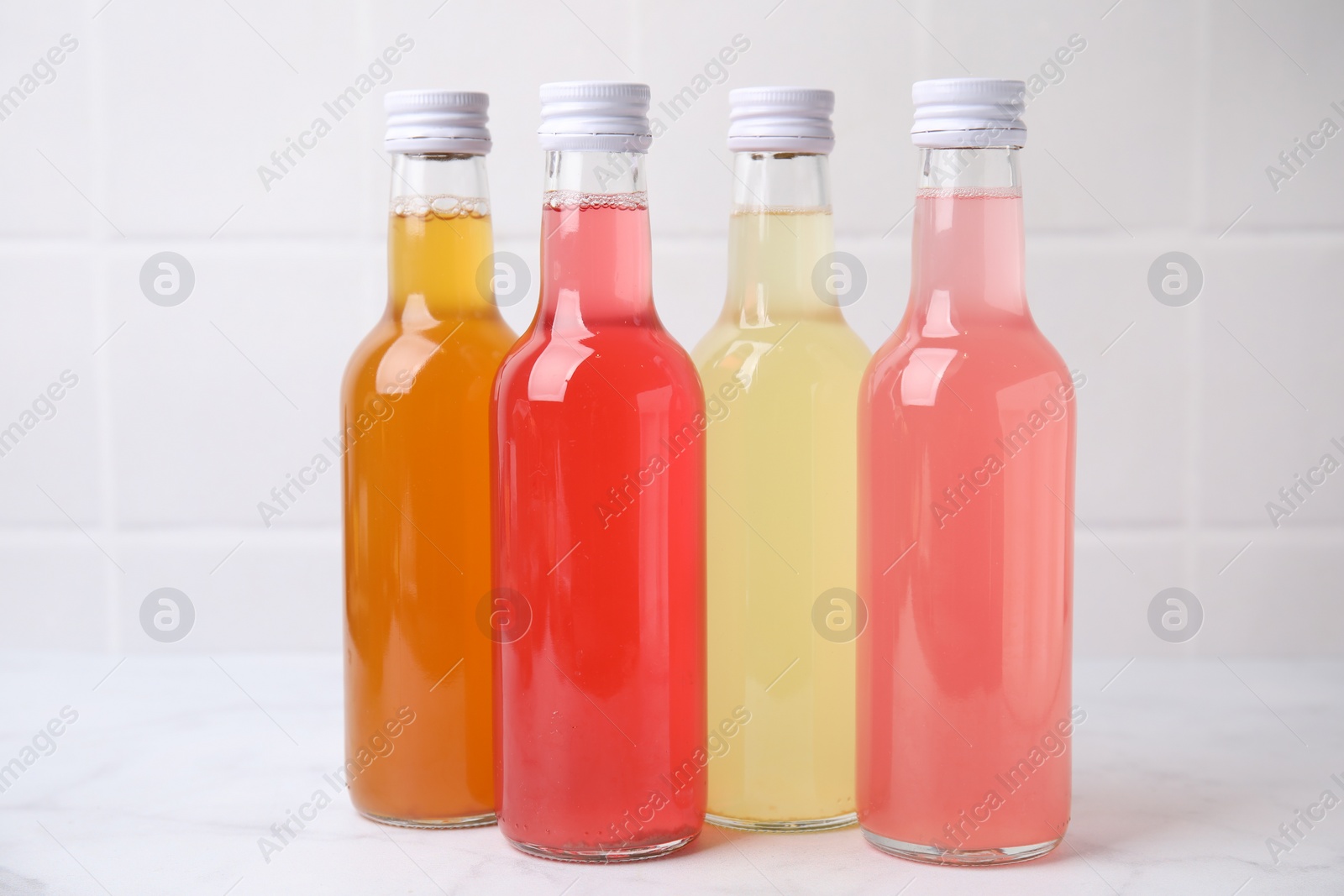 Photo of Delicious kombucha in glass bottles on white marble table