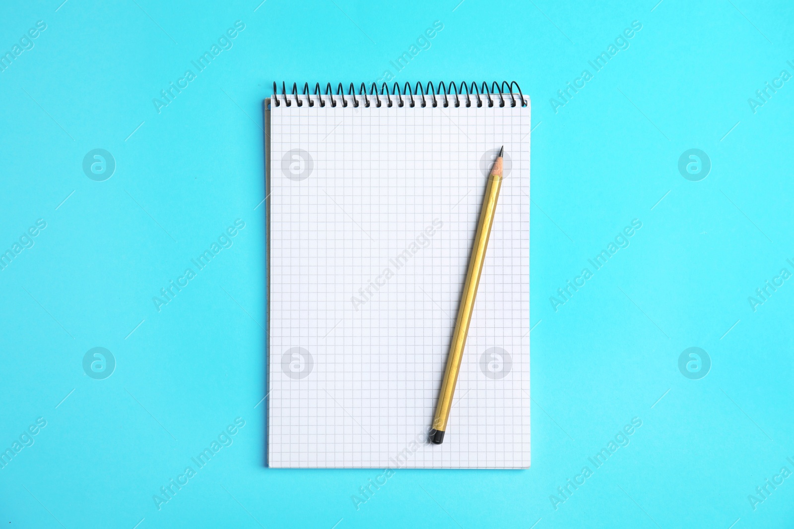 Photo of Empty notebook and pencil on color background, top view