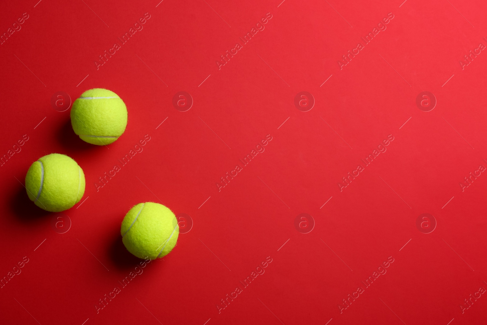 Photo of Tennis balls on red background, flat lay. Space for text