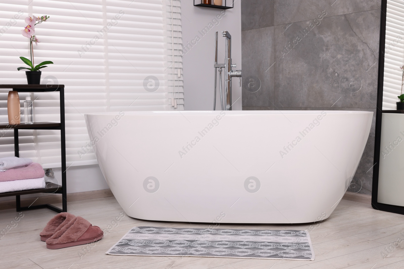 Photo of Stylish bathroom interior with soft bath mat and tub