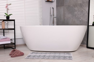 Photo of Stylish bathroom interior with soft bath mat and tub