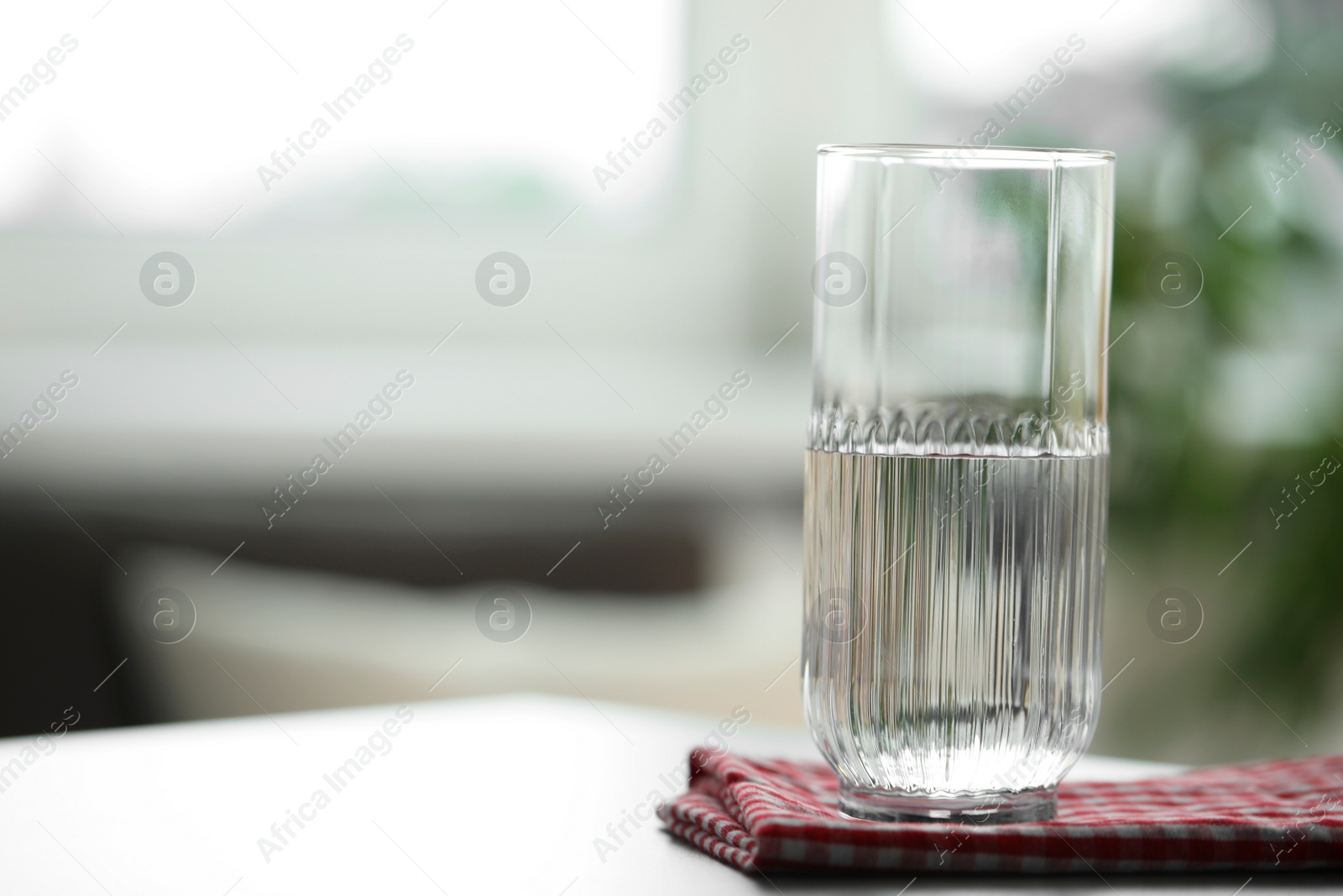 Photo of Glass of pure water on light table against blurred background, space for text