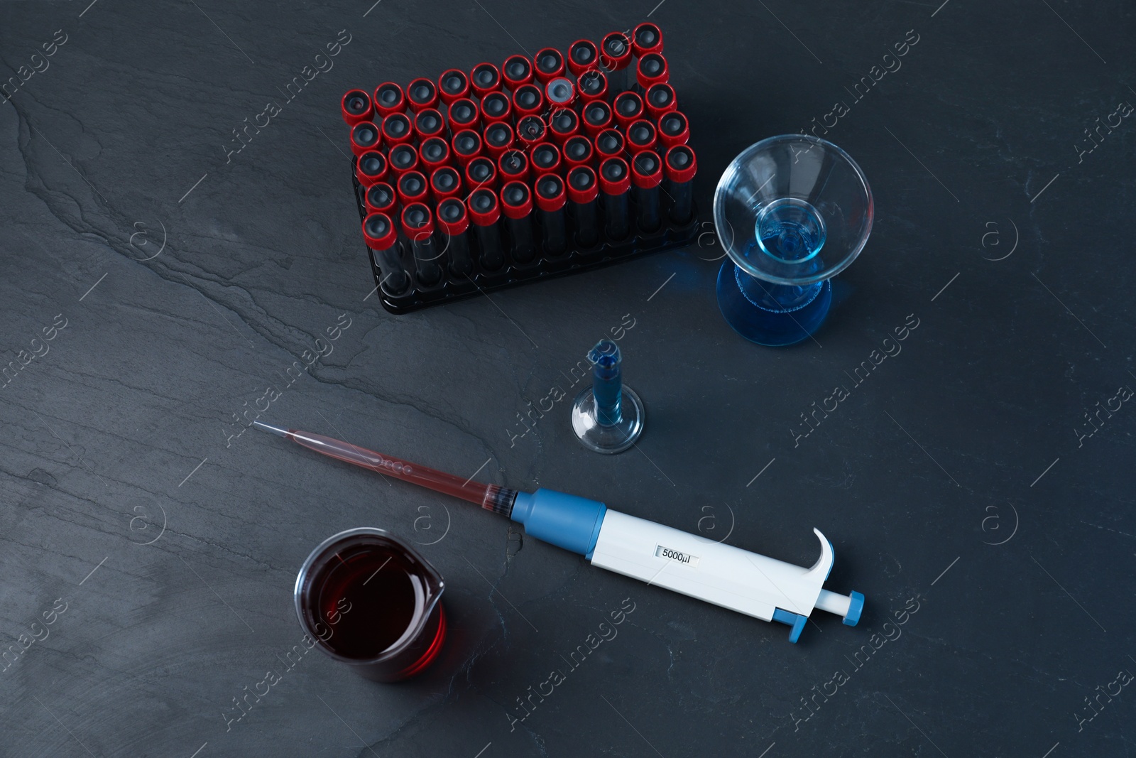 Photo of Laboratory analysis. Micropipette and different glassware on black table, flat lay