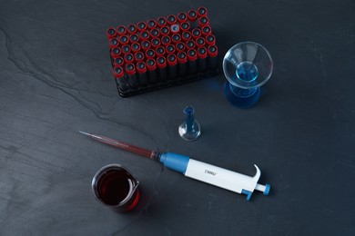 Laboratory analysis. Micropipette and different glassware on black table, flat lay