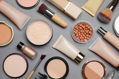 Photo of Face powders and other makeup products on grey background, flat lay