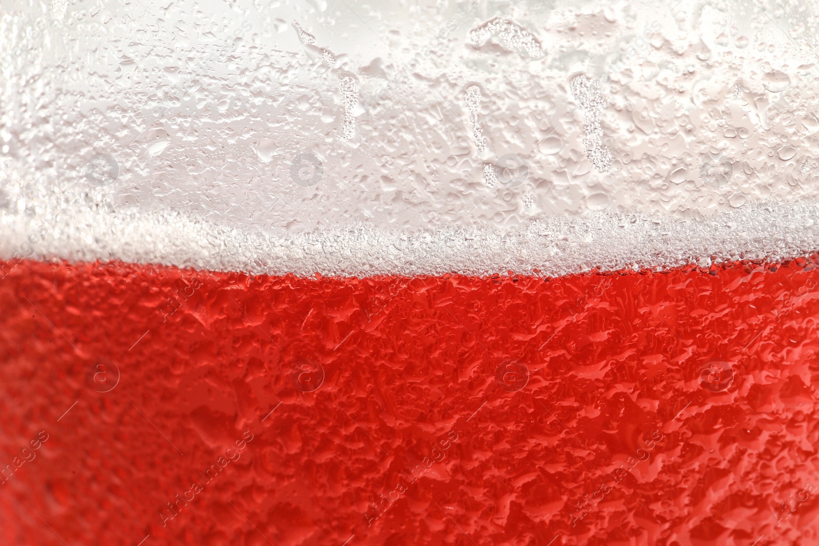 Photo of Glass of tasty red beer with foam, closeup