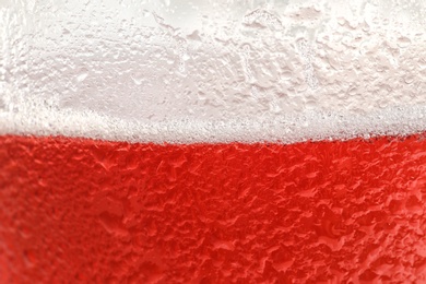 Photo of Glass of tasty red beer with foam, closeup