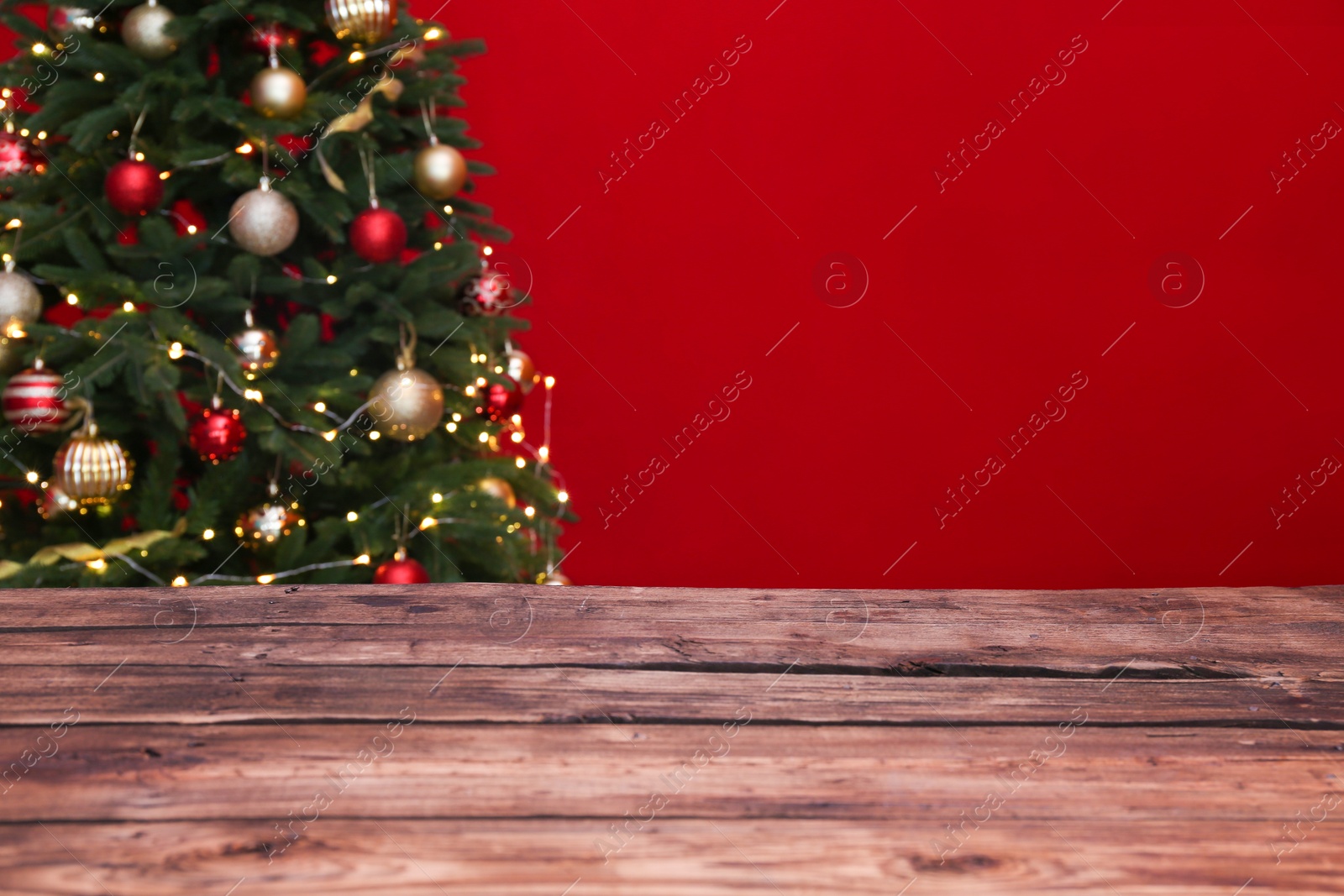 Photo of Wooden table and blurred Christmas tree with fairy lights on background