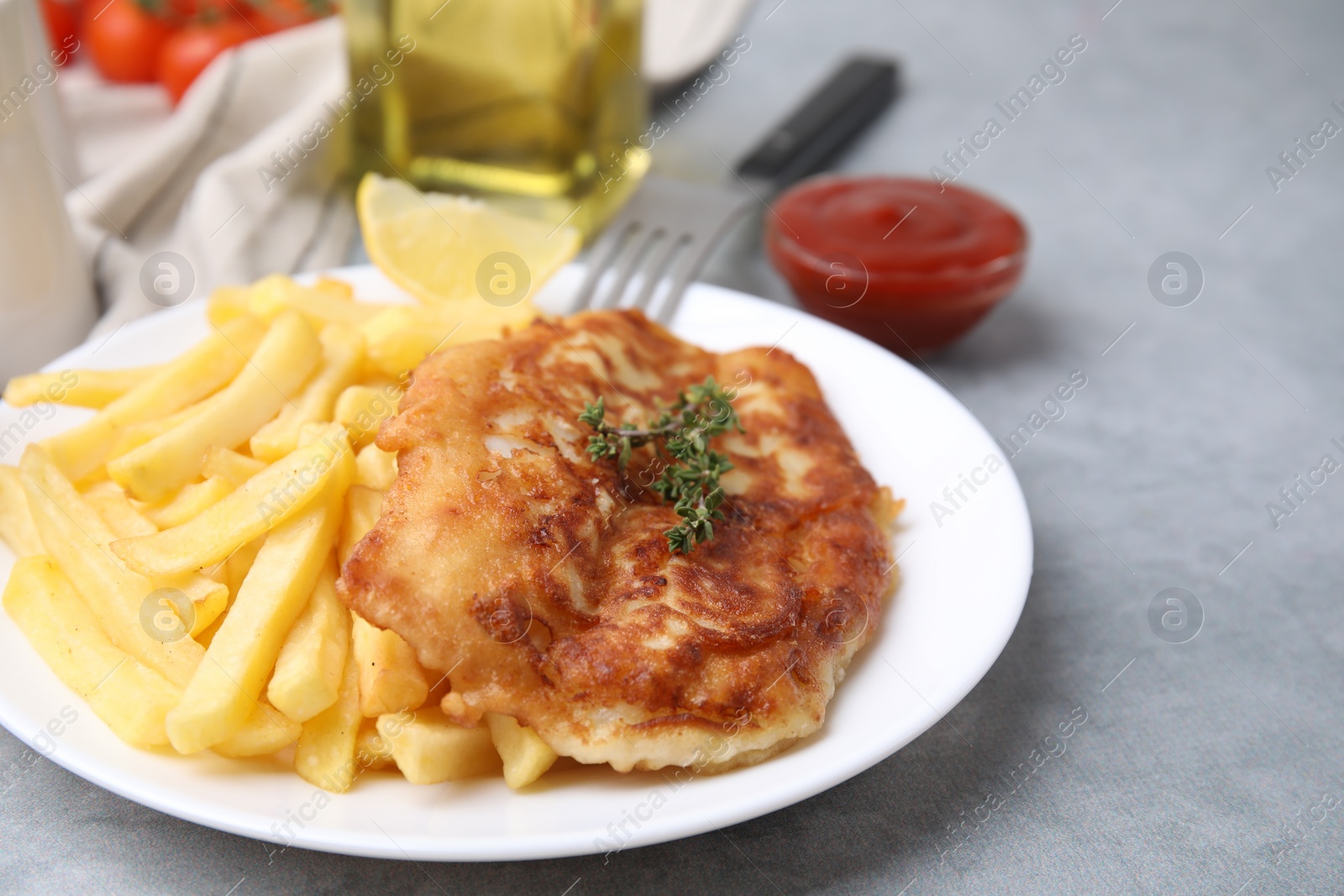 Photo of Tasty soda water battered fish, potato chips and lemon slice on light grey table