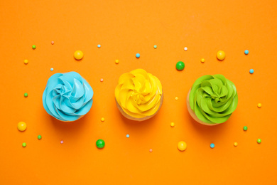 Colorful birthday cupcakes on orange background, flat lay