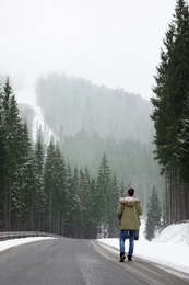 Man walking near snowy forest on winter day