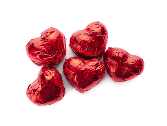 Photo of Heart shaped chocolate candies in red foil on white background, top view