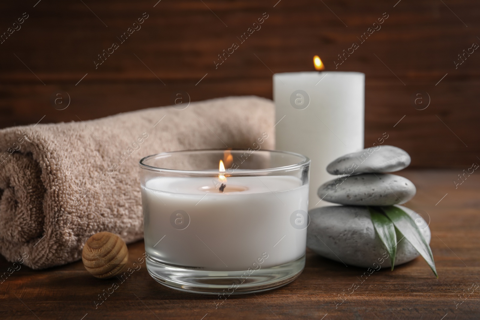 Photo of Beautiful composition with spa stones, towel and burning candles on wooden table