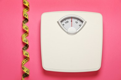 Photo of Weigh scales and measuring tape on pink background, flat lay. Overweight concept