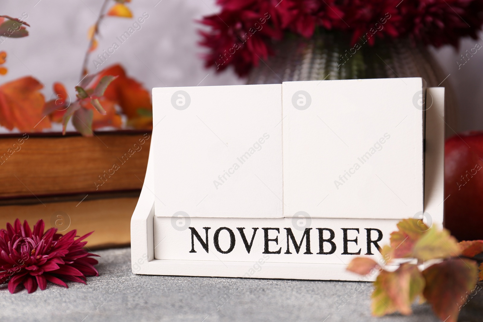 Photo of Thanksgiving day, holiday celebrated every fourth Thursday in November. Block calendar and autumn leaves on grey table, closeup