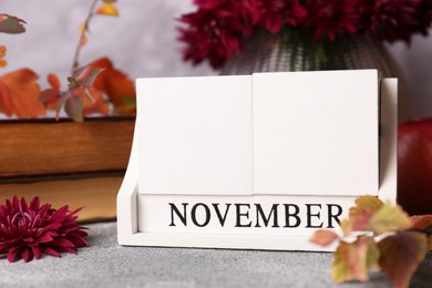 Photo of Thanksgiving day, holiday celebrated every fourth Thursday in November. Block calendar and autumn leaves on grey table, closeup