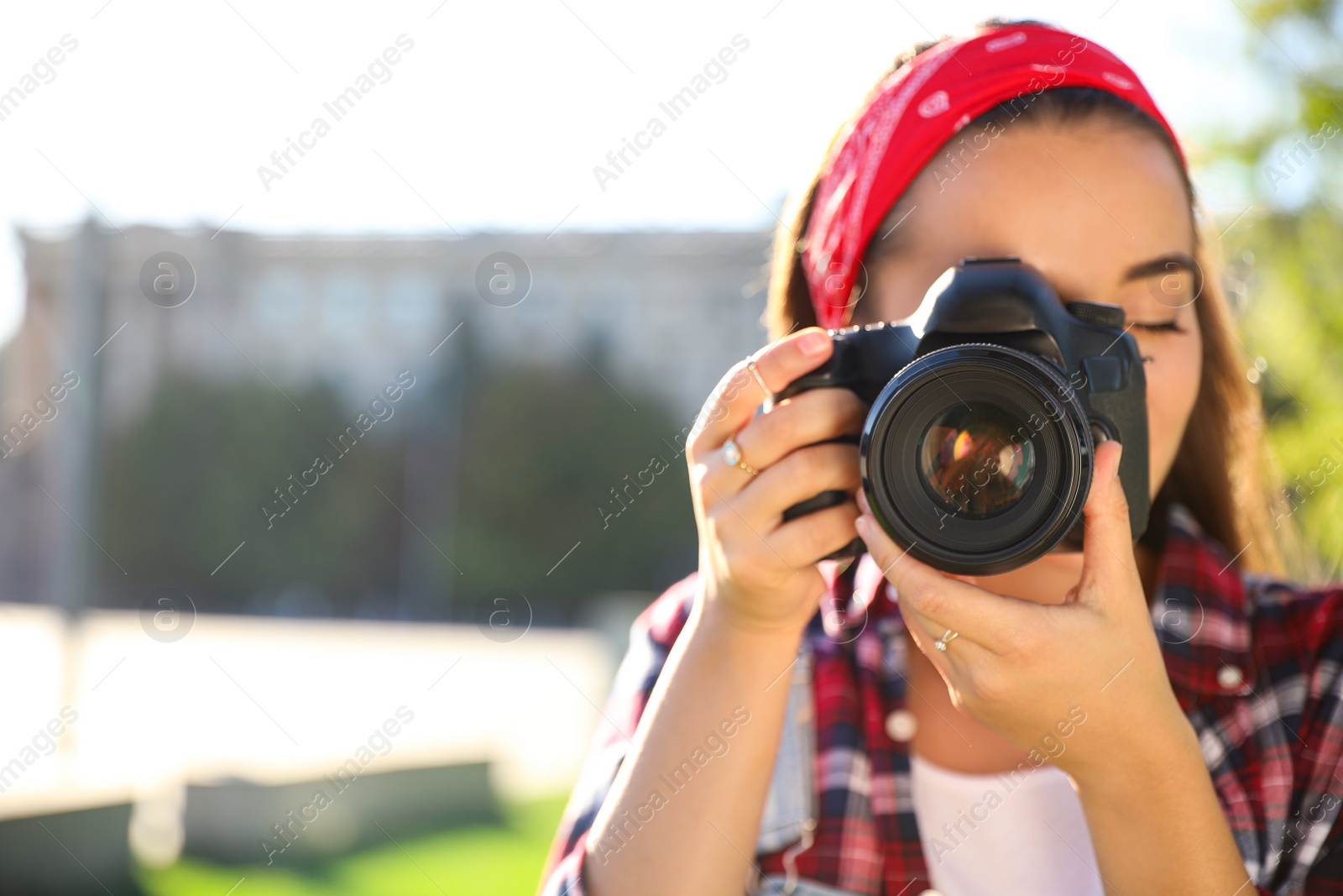 Photo of Young photographer taking picture with professional camera outdoors. Space for text