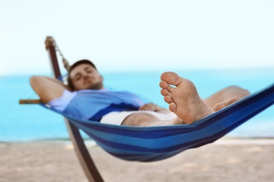 Young man lying in hammock at seaside. Summer vacation