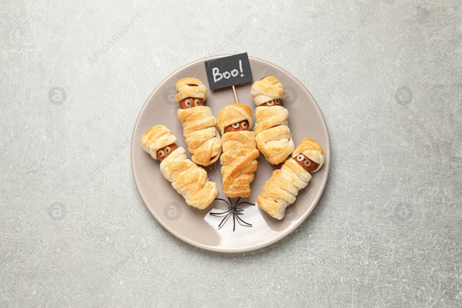 Photo of Spooky sausage mummies on light grey table, top view. Halloween treat