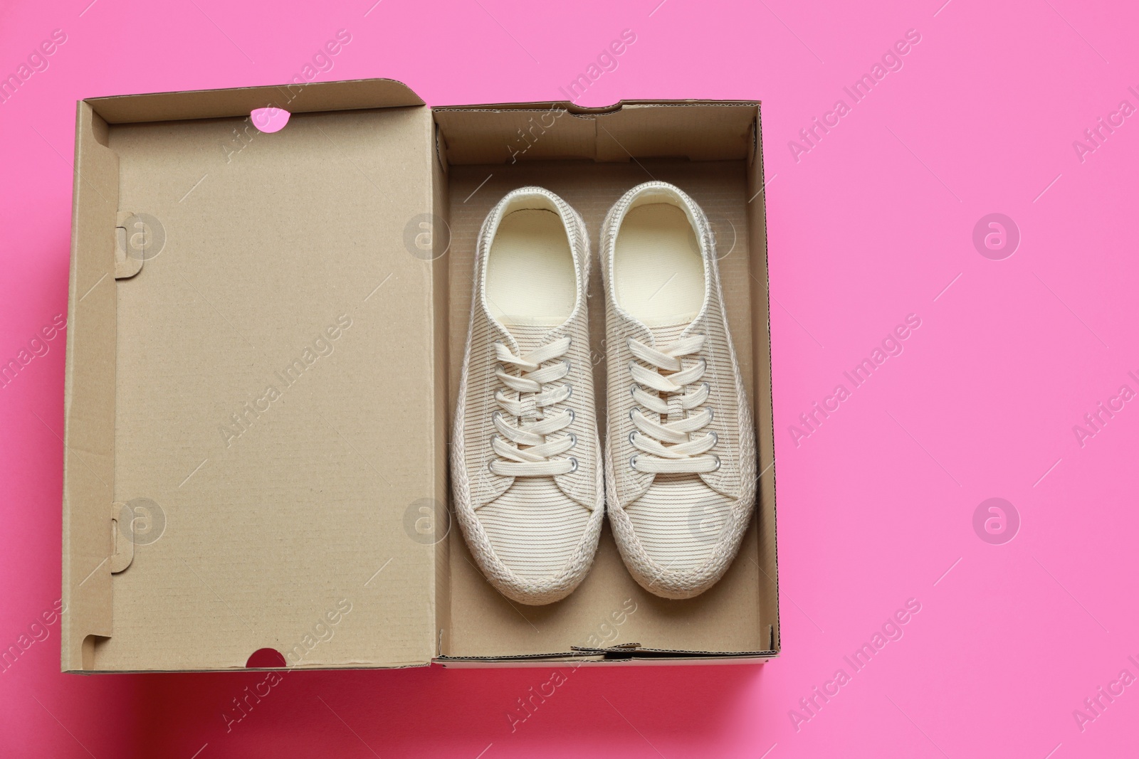 Photo of Comfortable shoes in cardboard box on pink background, top view