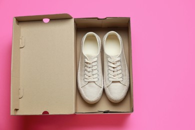 Photo of Comfortable shoes in cardboard box on pink background, top view