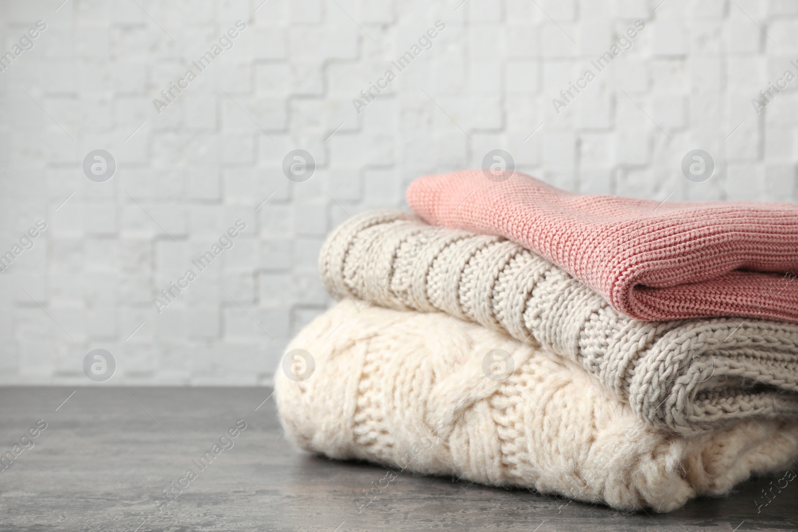 Photo of Stack of folded knitted sweaters on table. Space for text