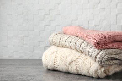 Stack of folded knitted sweaters on table. Space for text