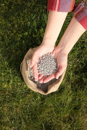 Photo of Woman with fertilizer on green grass outdoors, top view