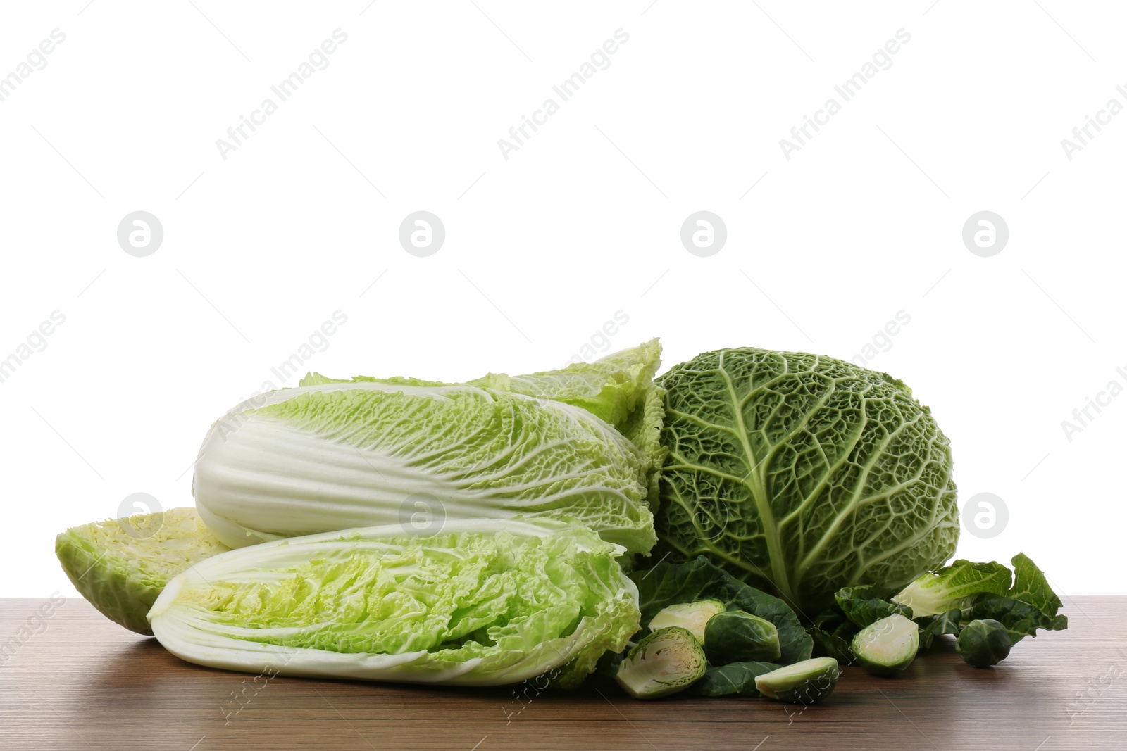 Photo of Different types of cut cabbage on wooden table against white background