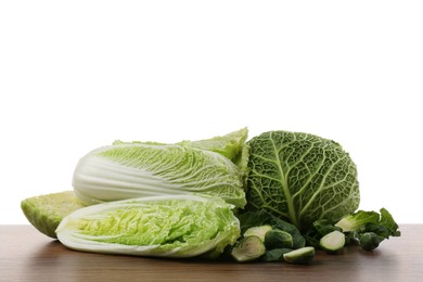 Photo of Different types of cut cabbage on wooden table against white background