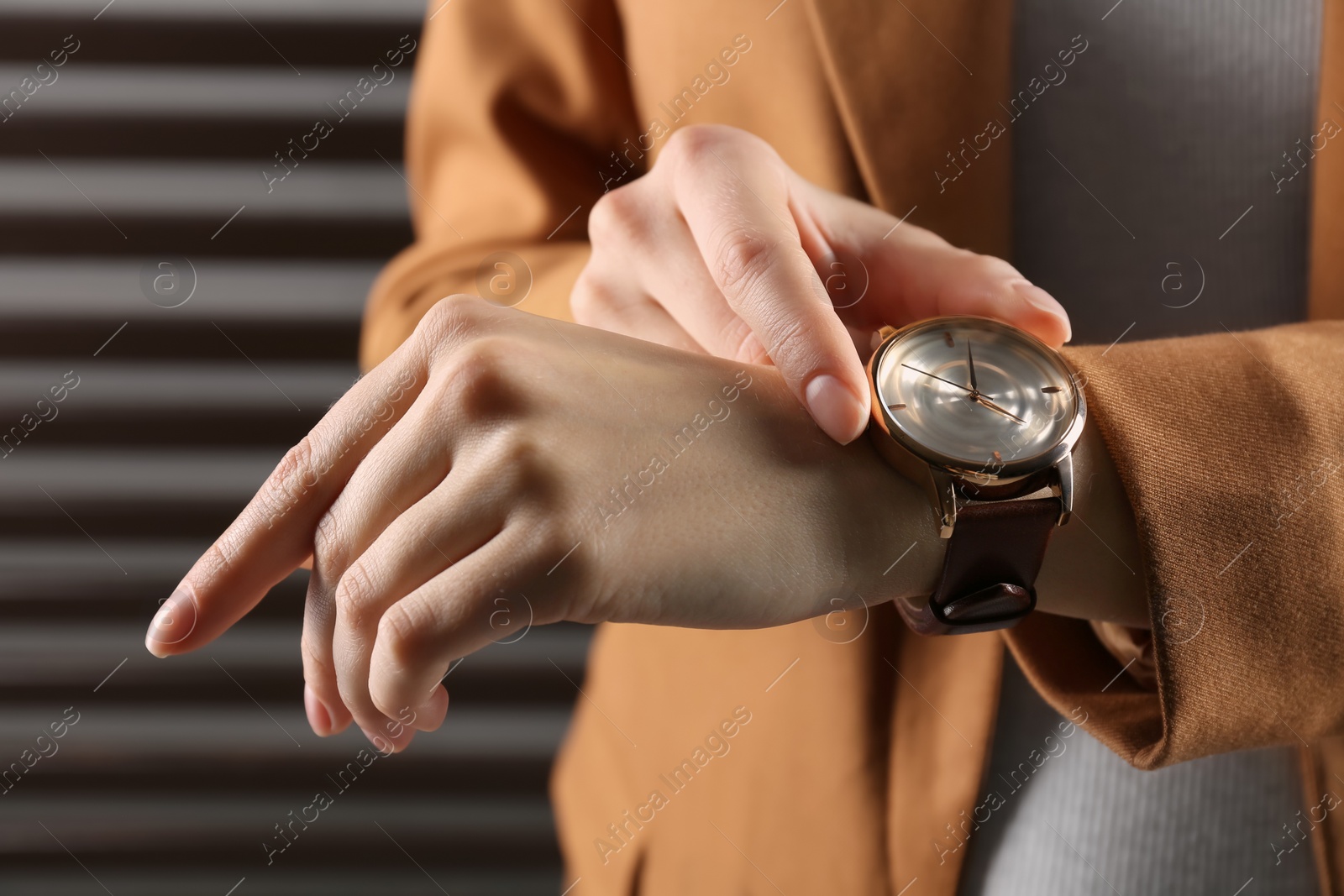 Photo of Woman wearing luxury wristwatch on dark grey background, closeup