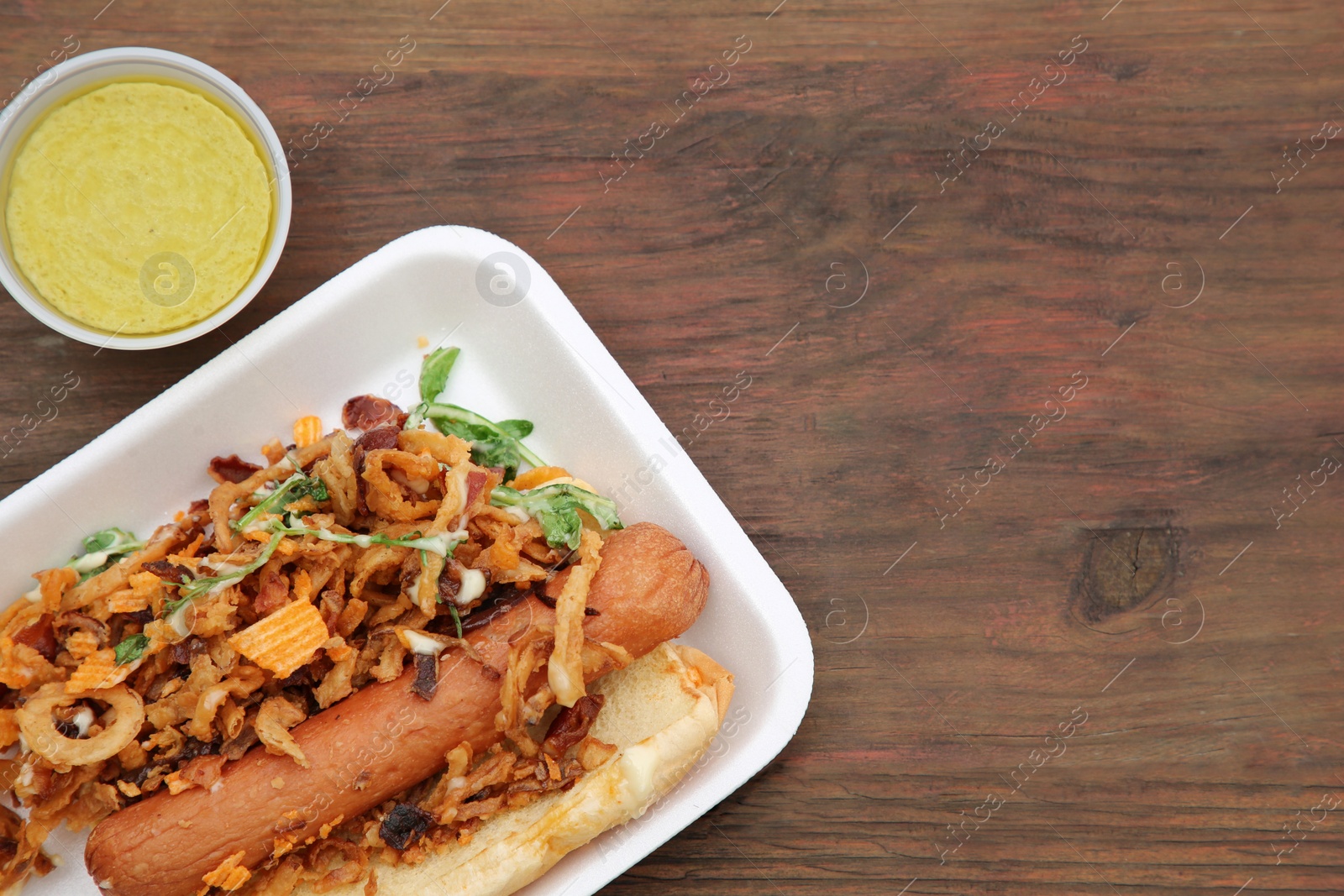 Photo of Fresh delicious hot dog with sauce on wooden table, flat lay. Space for text