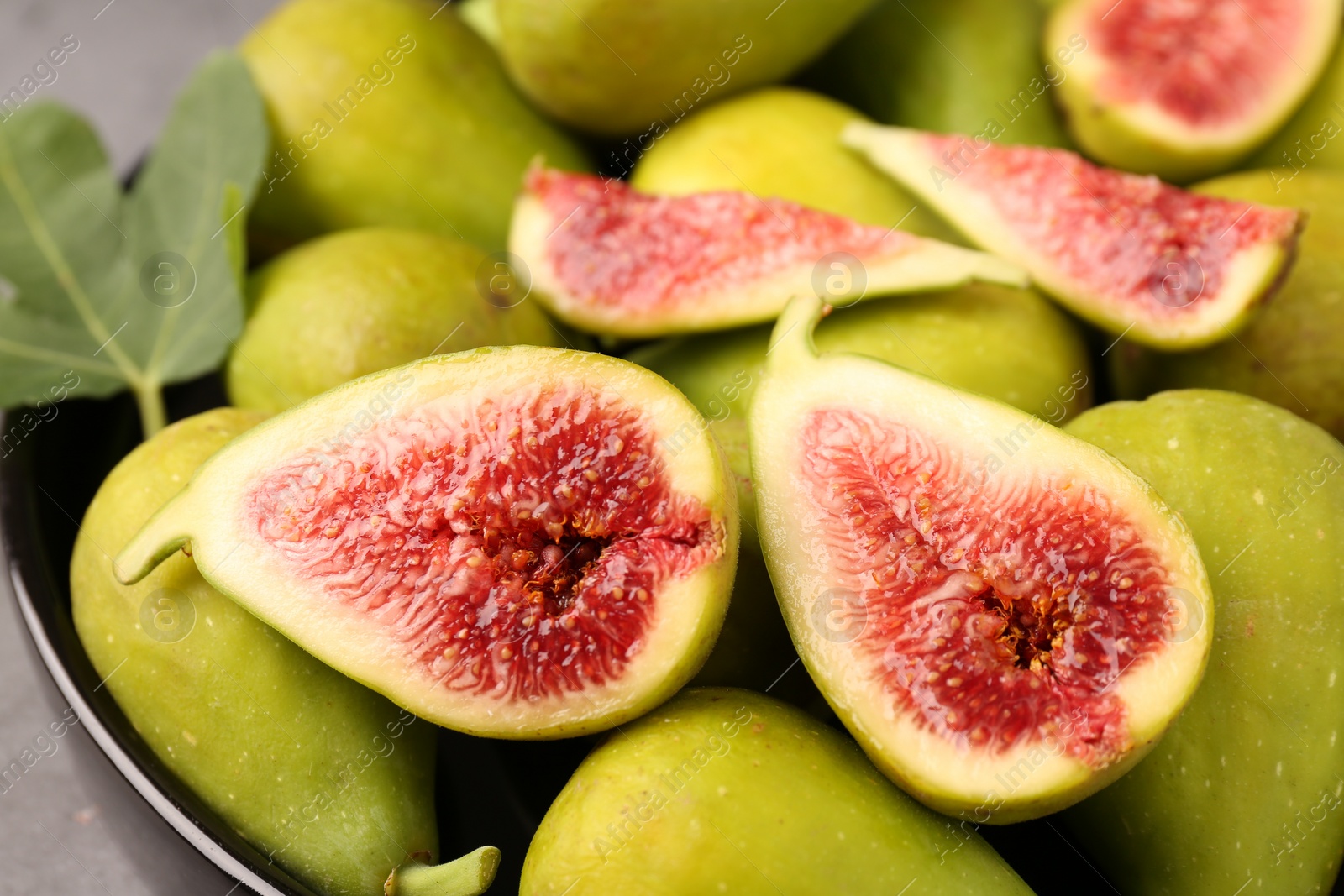 Photo of Cut and whole green figs on plate, closeup